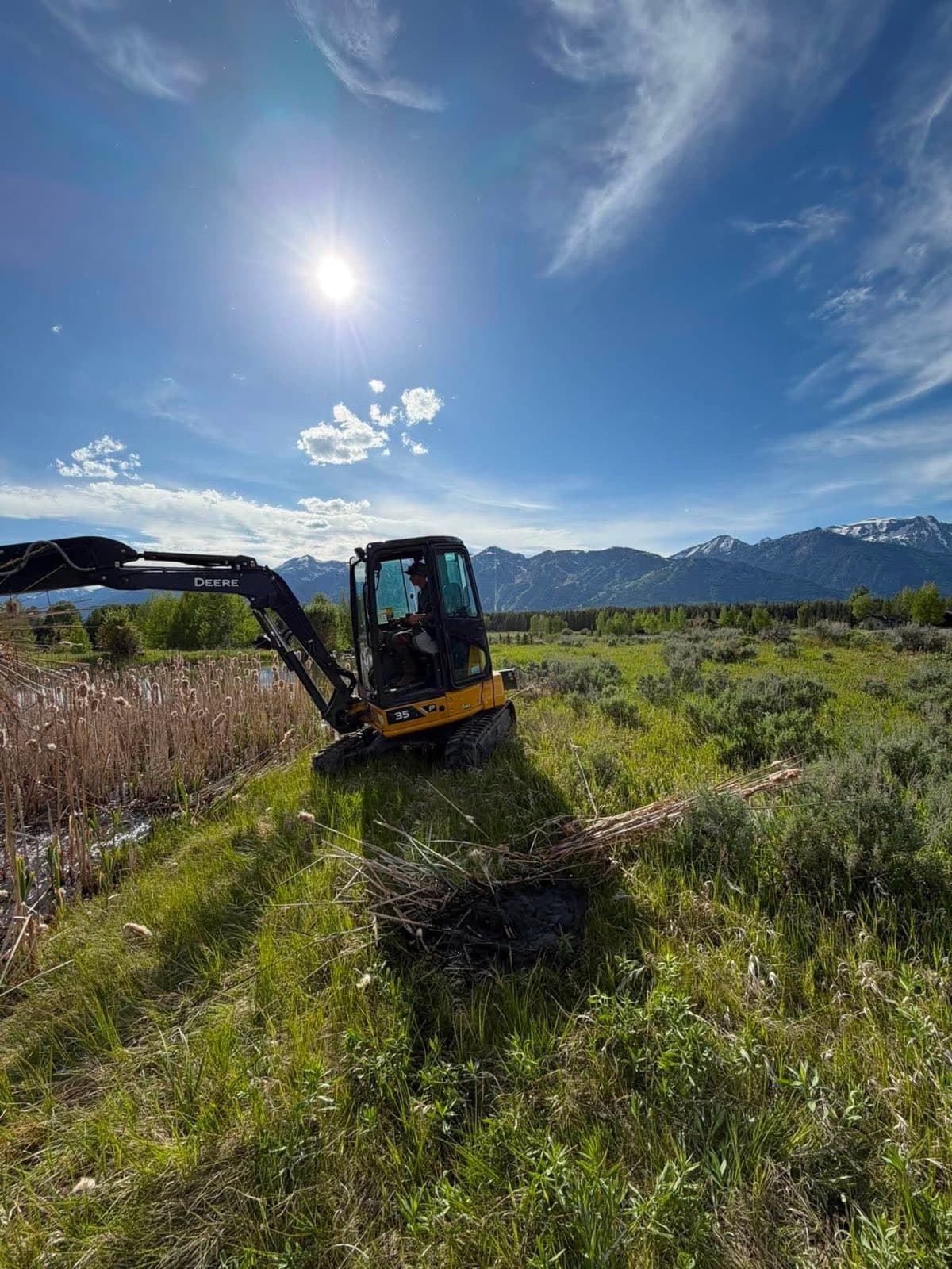 Stradley Landscape running a John Deere 35P excavator with the Tetons behind