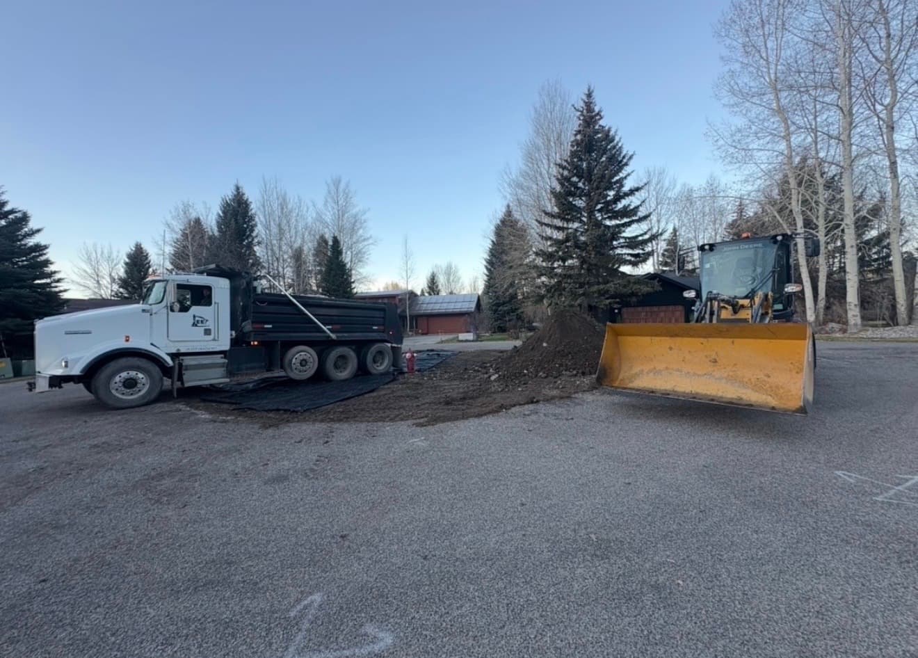 John Deere wheel loader and dump truck moving soil on a Jackson Hole job